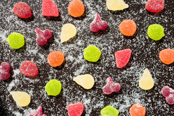 Multi-colored marmalade and sprinkled sugar on a black background. - Photo, Image