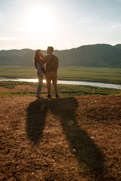 interracial couple on a cliff in valley in the sunset  - 写真・画像