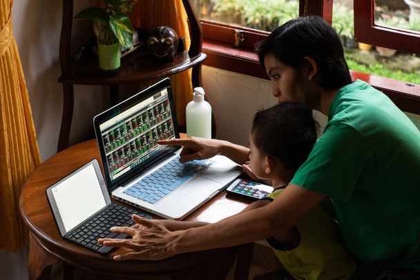 a mother do her work from home while caring her toddler son. During the current Covid-19 pandemic, Lockdown was carried out in several countries. They work from home to reduce the spread of the virus - Photo, Image