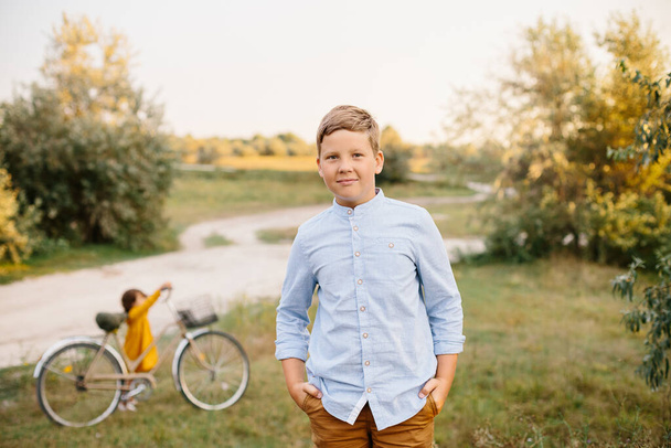 Portrait of 10 years caucasian boy with blonde hair wearing blue shirt and mustard trousers standing in fields. Holiday domestic tourism - Photo, Image