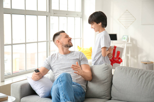 Pequeno filho com presente cumprimentando seu pai em casa
 - Foto, Imagem