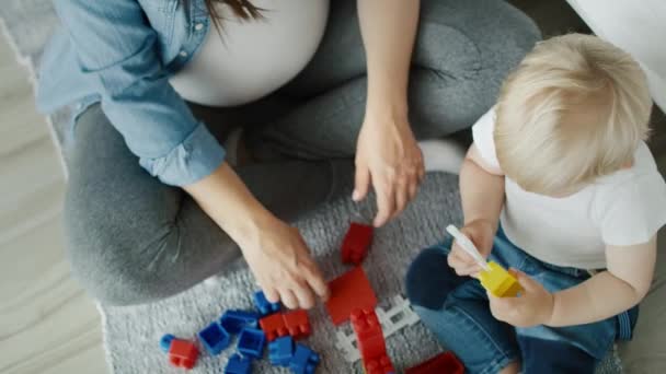 Vista superior de vídeo de la madre jugando bloques de juguete con hijo. Fotografía con cámara de helio RED en 8K
  - Metraje, vídeo