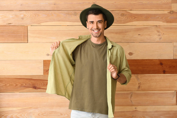Mężczyzna w stylowej koszulce na drewnianym tle - Zdjęcie, obraz
