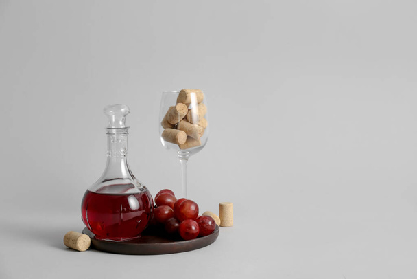 Decanter of wine with glass and corks on grey background - Photo, Image