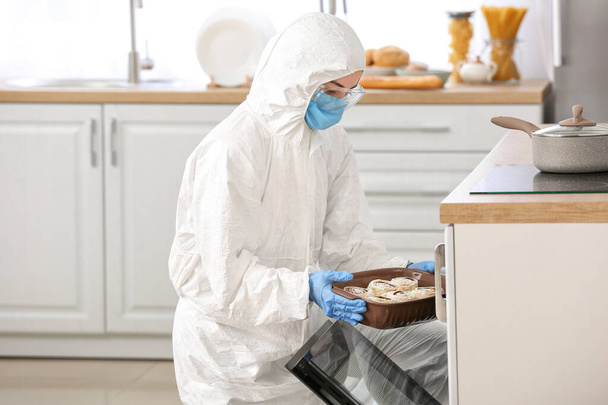 Женщина в костюме биологической опасности готовит на кухне
 - Фото, изображение