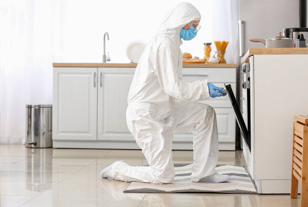 Woman in biohazard suit cooking in kitchen - Фото, зображення