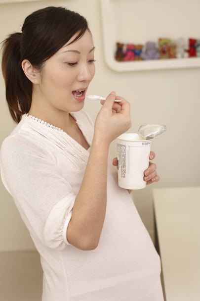 Pregnant woman eating yoghurt - Fotó, kép