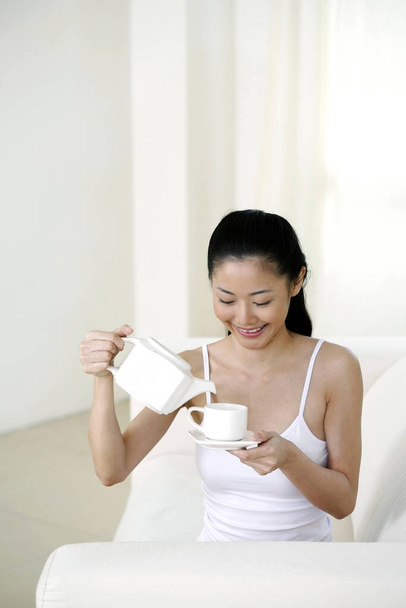 Woman pouring tea into cup - Zdjęcie, obraz