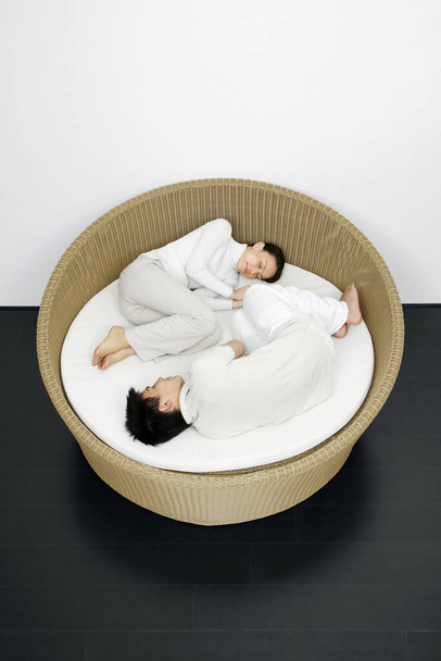 Woman and man curled up in a rattan bed - Foto, immagini