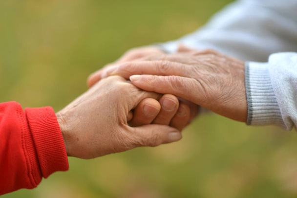 seniorzy trzymający się za ręce w parku - Zdjęcie, obraz