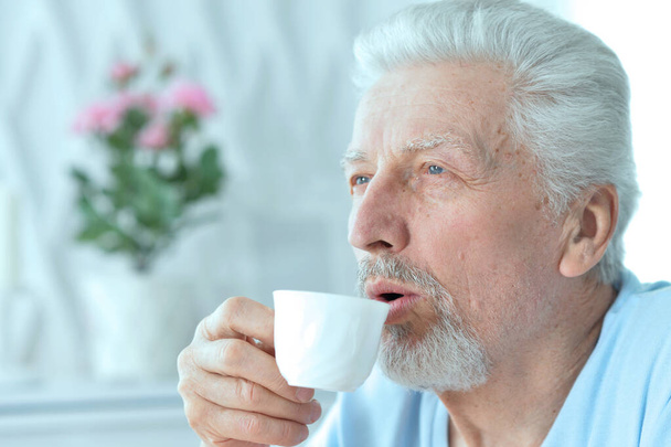 Portrait of smiling senior man drinking coffee  at home  - Photo, Image