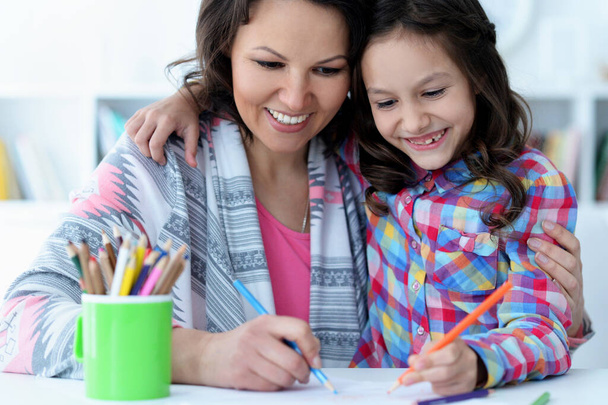 little cute girl with mother drawing at the table at home - Foto, Imagem