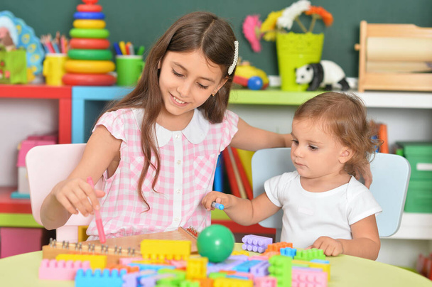 Дві маленькі дівчата грають з барвистими пластиковими блоками
 - Фото, зображення