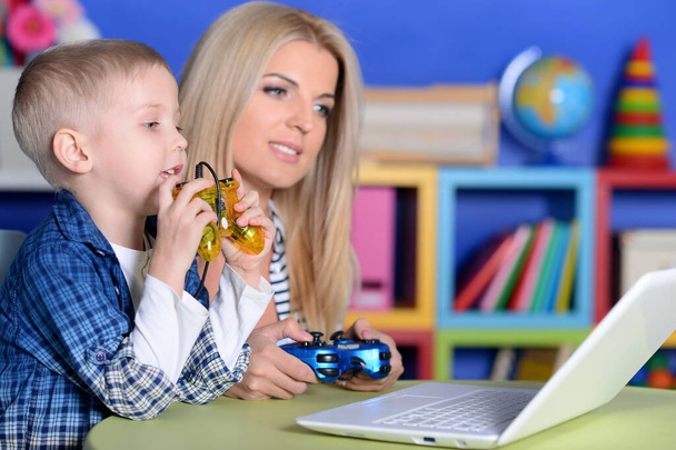 ラップトップでコンピュータゲームをプレイする母親と息子 - 写真・画像