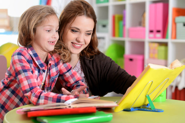Portrait d'une belle petite fille mignonne avec sa mère faisant ses devoirs
  - Photo, image