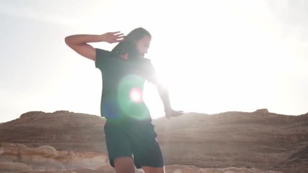 ハンサムな男は、太陽の下で砂漠の中で恍惚ダンスを踊る急速なスローモーション - 映像、動画