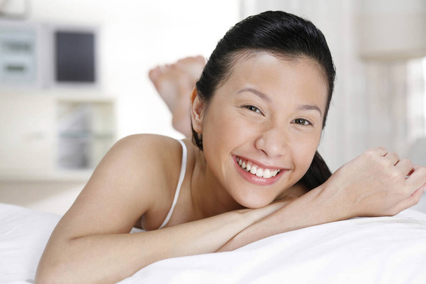 Woman lying forward on the bed, smiling at the camera - Fotoğraf, Görsel