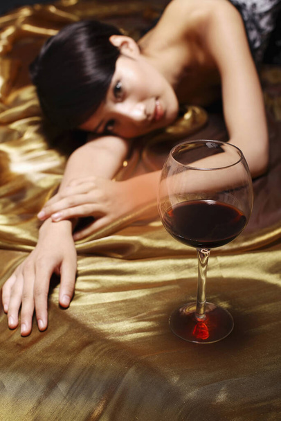 Woman lying on her arm looking at wine glass - Photo, image