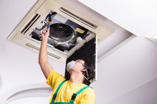 Junger Reparateur repariert Klimaanlage an der Decke - Foto, Bild