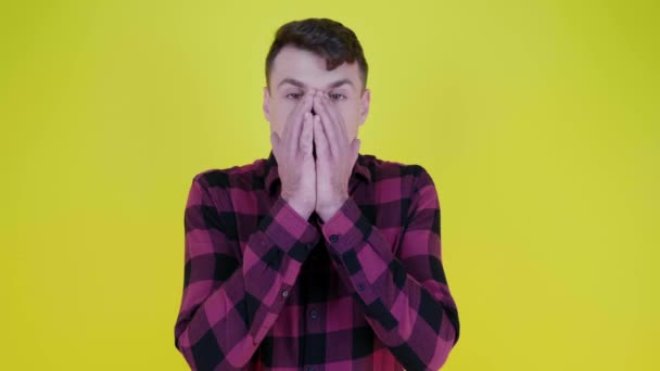 Hombre sorprendido por lo que ve, cubre su cara con sus manos sobre fondo amarillo
 - Metraje, vídeo