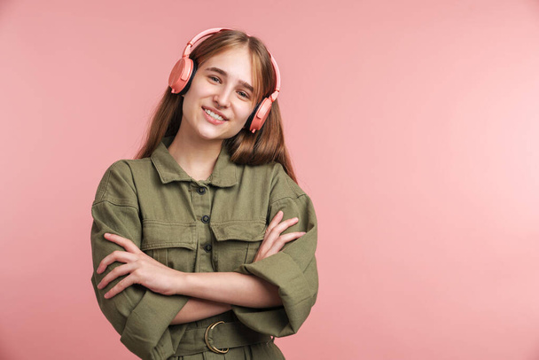 Photo of happy caucasian woman using headphones and smiling isolated over pink background - Foto, imagen