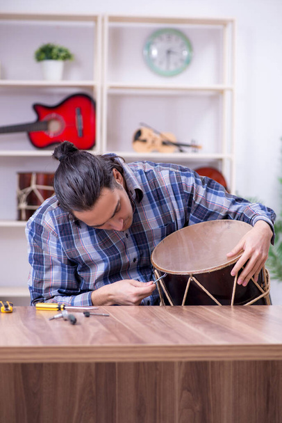 Молодой красивый ремонтник чинит барабан - Фото, изображение