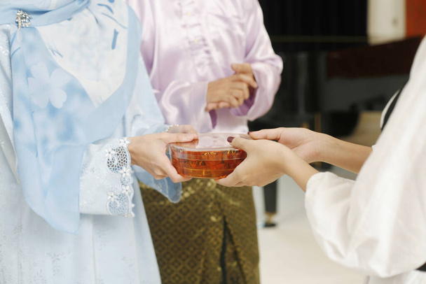 Woman giving her friend a box of traditional cookies during Hari Raya - Foto, Imagen