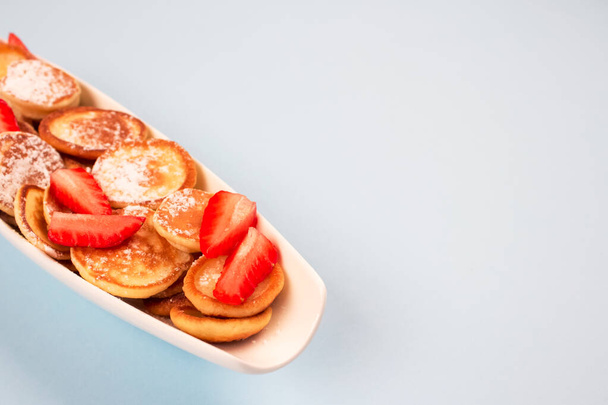 Κοντινό πλάνο των μίνι τηγανίτες δημητριακών με φράουλες σε λευκό πιάτο σε μπλε φόντο με αντίγραφο χώρο για τη συνταγή ή το κείμενό σας. Πρωινό, μοντέρνο φαγητό έννοια - Φωτογραφία, εικόνα