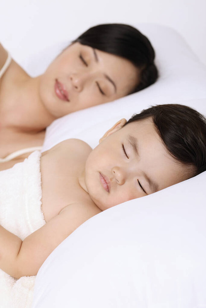 Woman sleeping beside baby girl - 写真・画像