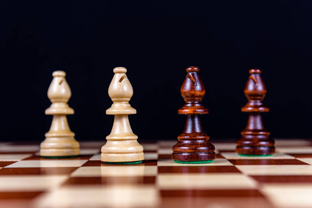 quatro bispos de xadrez em um tabuleiro de xadrez em um fundo preto
 - Foto, Imagem