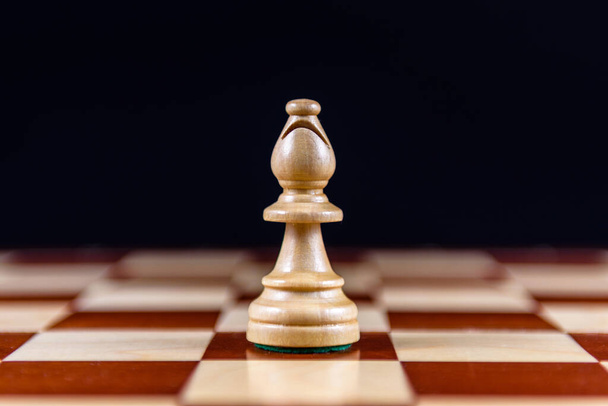a white chess Bishop stands on a chessboard on a black background - Foto, Imagem
