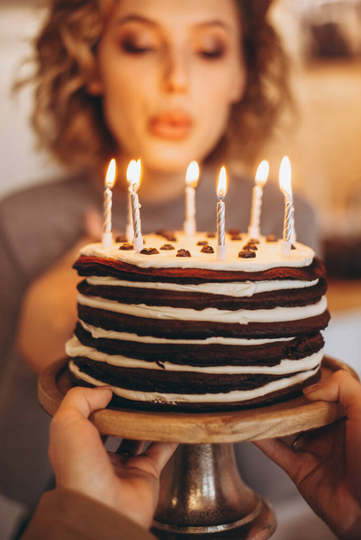 Make a wish. Young pretty girl is about to make a wish and blow all candles: homemade cake with burning candles, selective focus, noise effect - Фото, изображение