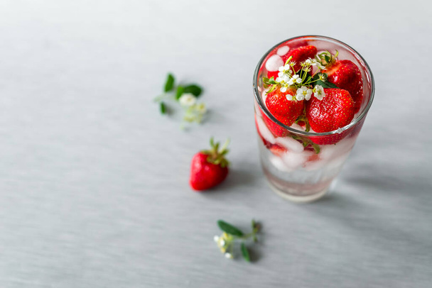 ποτήρι με ένα καλοκαιρινό παγωμένο διαυγές ανθρακούχο ποτό, πάγο και φράουλες. Δροσιστική δροσιά - Φωτογραφία, εικόνα