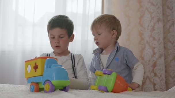 oktatási játékok, kis aranyos fiúk, testvérek fejleszteni kreatív gondolkodás játszik a biztonsági műanyag autók a szobában - Felvétel, videó