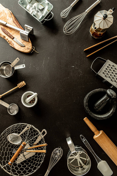Kitchen utensils (cooking tools) on black chalkboard background. Kitchenware collection captured from above (top view, flat lay). Layout with free copy (text) space.  - Zdjęcie, obraz