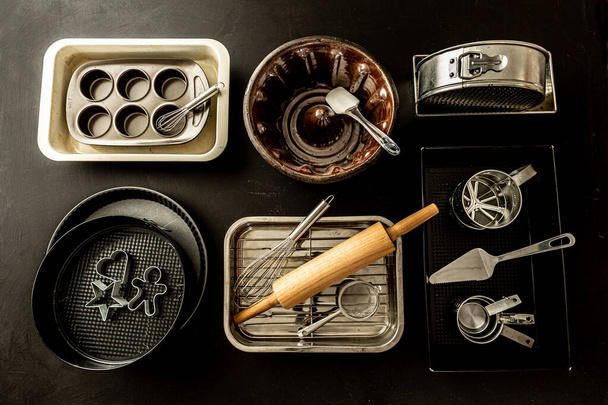 Oven bakeware - baking tins, cake moulds and kitchen utensils. Collection captured from above (top view, flat lay). Black chalkboard background. - Zdjęcie, obraz