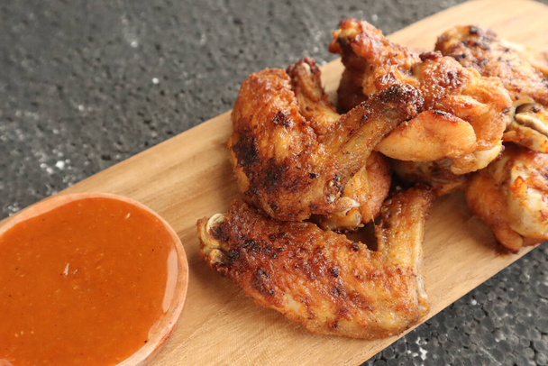 Νόστιμα φτερούγες κοτόπουλου, ψητές ή τηγανητές φτερούγες κοτόπουλου σερβιρισμένες με καυτερή πικάντικη σάλτσα μπάρμπεκιου, κοντινή εικόνα - Φωτογραφία, εικόνα