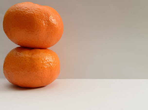 Duas tangerinas em cima uma da outra em fundo branco
 - Foto, Imagem