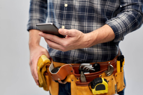 worker or builder with phone and working tools - 写真・画像