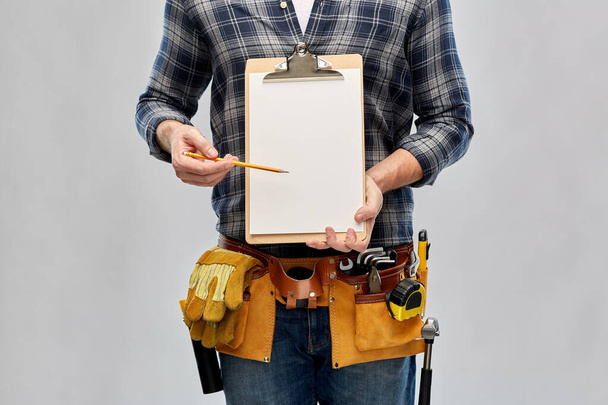 builder with clipboard, pencil and working tools - Foto, afbeelding