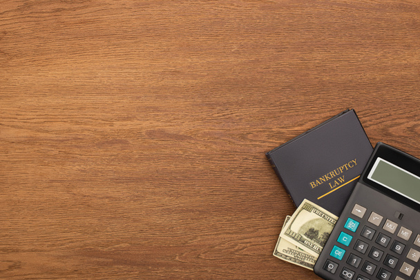 İflas hukuk kitabı, para ve hesap makinesinin ahşap zemin üzerindeki üst görünümü - Fotoğraf, Görsel