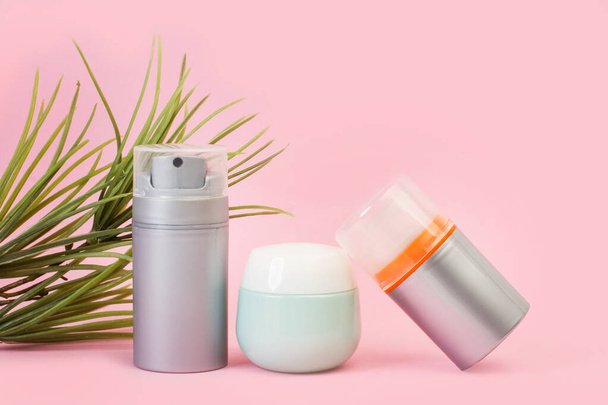 Drei Behälter mit Feuchtigkeitscreme auf rosa Hintergrund - Foto, Bild