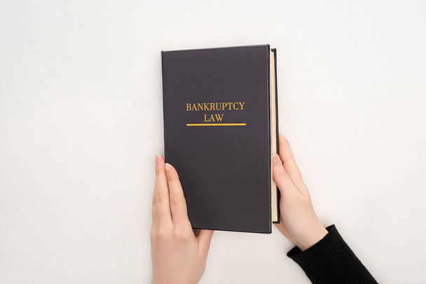 частичный взгляд женщины, держащей книгу законов о банкротстве на белом фоне
 - Фото, изображение