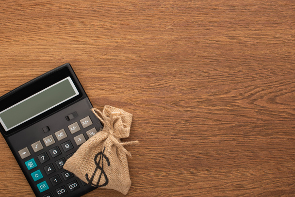vista superior do saco de dinheiro, calculadora no fundo de madeira
 - Foto, Imagem