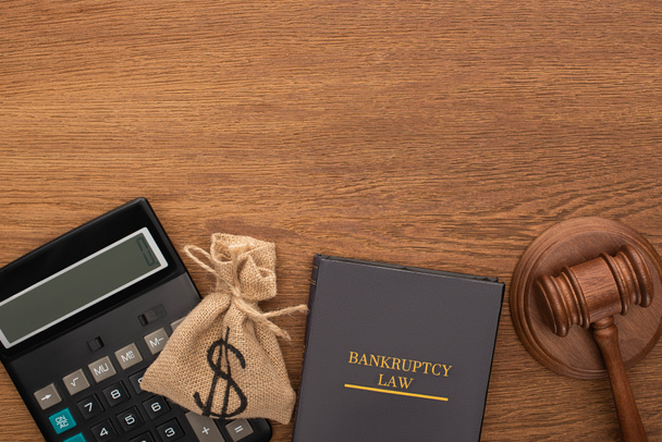 top view of bankruptcy law book, money bag, calculator and gavel on wooden background - Fotografie, Obrázek