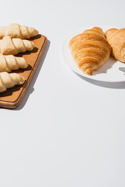 fresh baked and raw croissants on white background - Fotoğraf, Görsel