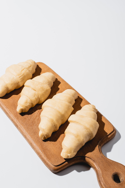 raw fresh croissants on wooden cutting board on white background - Foto, imagen