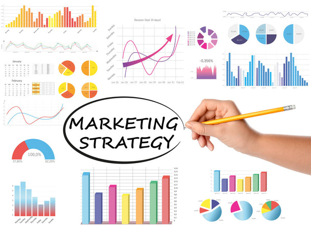 Woman writing words Marketing strategy and charts on white background, closeup - Foto, imagen