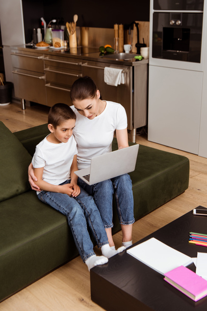 Anya és fia a laptop használata az online oktatás során otthon  - Fotó, kép