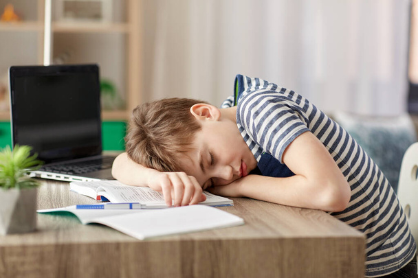 κουρασμένος μαθητής αγόρι κοιμάται στο γραφείο στο σπίτι - Φωτογραφία, εικόνα